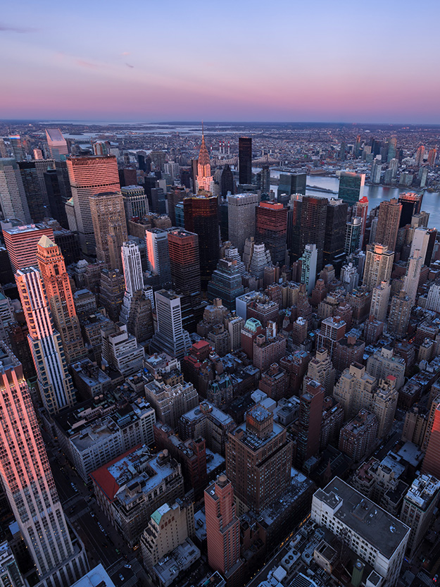 Aerial view of the Manhattan skyline during sunset with the iconic Empire State Building prominently featured.