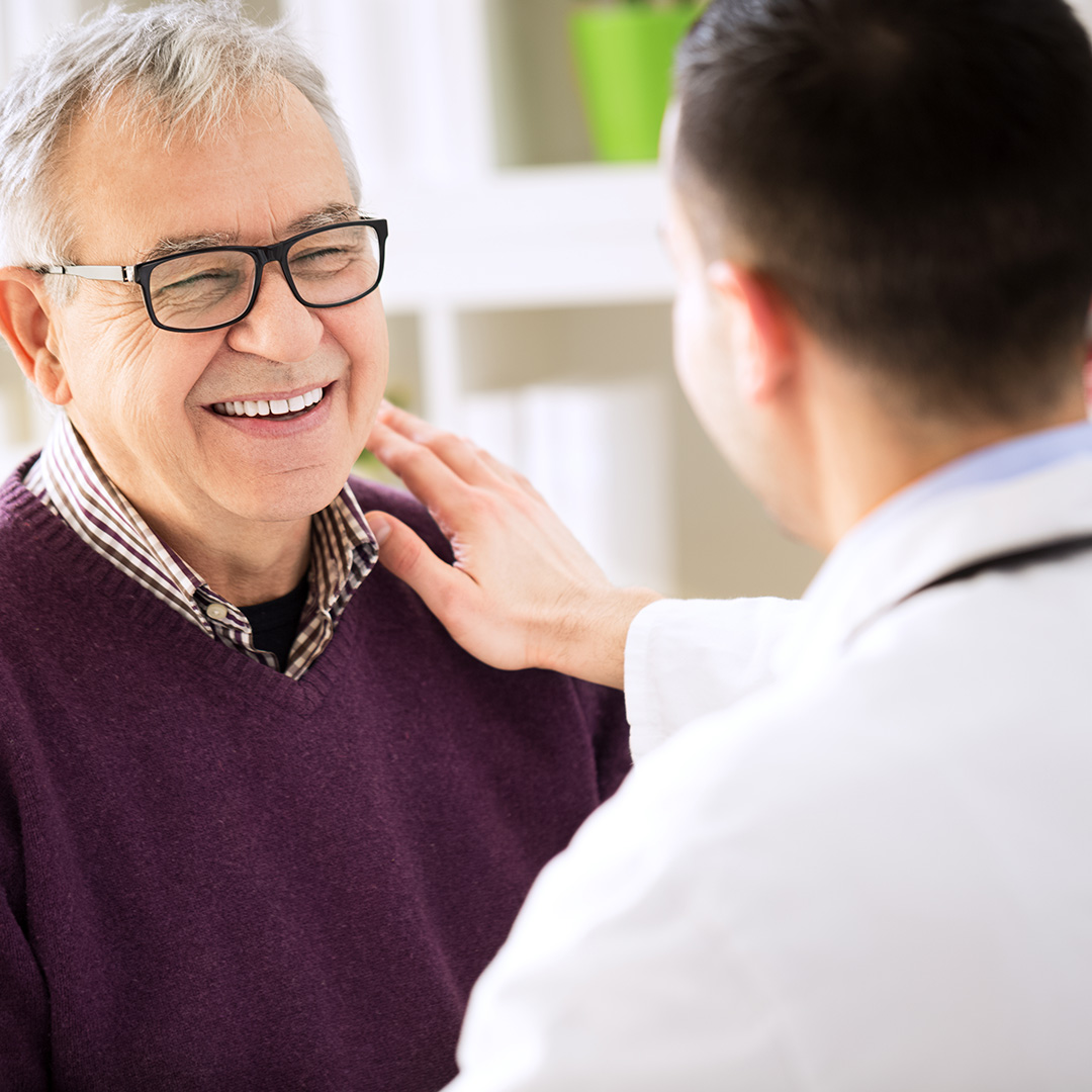 The image depicts an elderly man receiving a medical examination from a healthcare professional in a clinical setting.